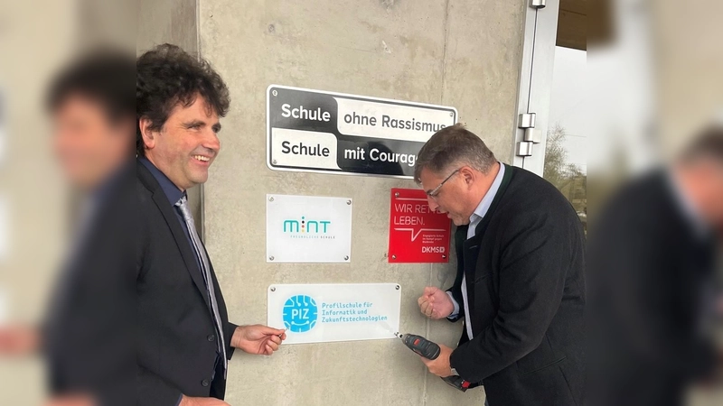 Landrat Stefan Löwl (rechts) und Christoph Strödecke, Schulleiter des Gymnasiums Markt Indersdorf, beim Anbringen der Auszeichnung „Profilschule für Informatik und Zukunftstechnologien“. (Foto: Landratsamt Dachau / Steffen Varga)