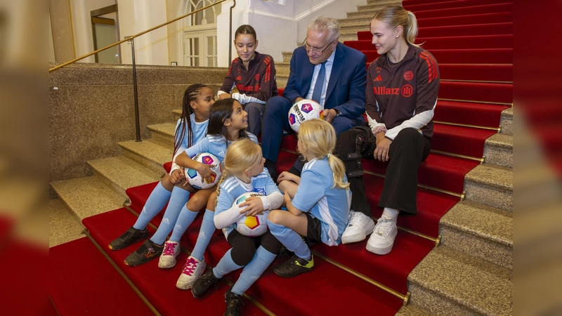 Fachgespräch auf dem roten Teppich: Sportminister Joachim Herrmann sowie die FC-Bayern-Spielerinnen Carla Schwarz und Nike Herrmann mit den „Mädchen an den Ball”-Mädchen Anna, Lea, Maria, Adna, Leni und Ayse. (Foto: Bernd Feil / Biku gGmbH)