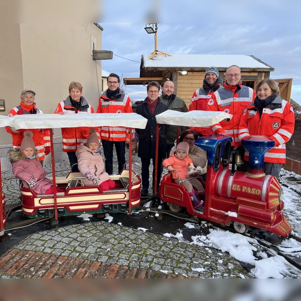 Sie begleiten den Start der Bahn (von links): Gudrun Boer, Angelika Gumowski, Dennis Behrendt, Florian Hartmann, Timo Weiersmüller, Matthias Malcharczik, Bernhard Seidenath und Angelika Kniesl. Im Zug sitzen (von links) Johanna,Vanessa und die kleine Liv mit ihrer Mama Melanie Vieregg. (Foto: BRK)