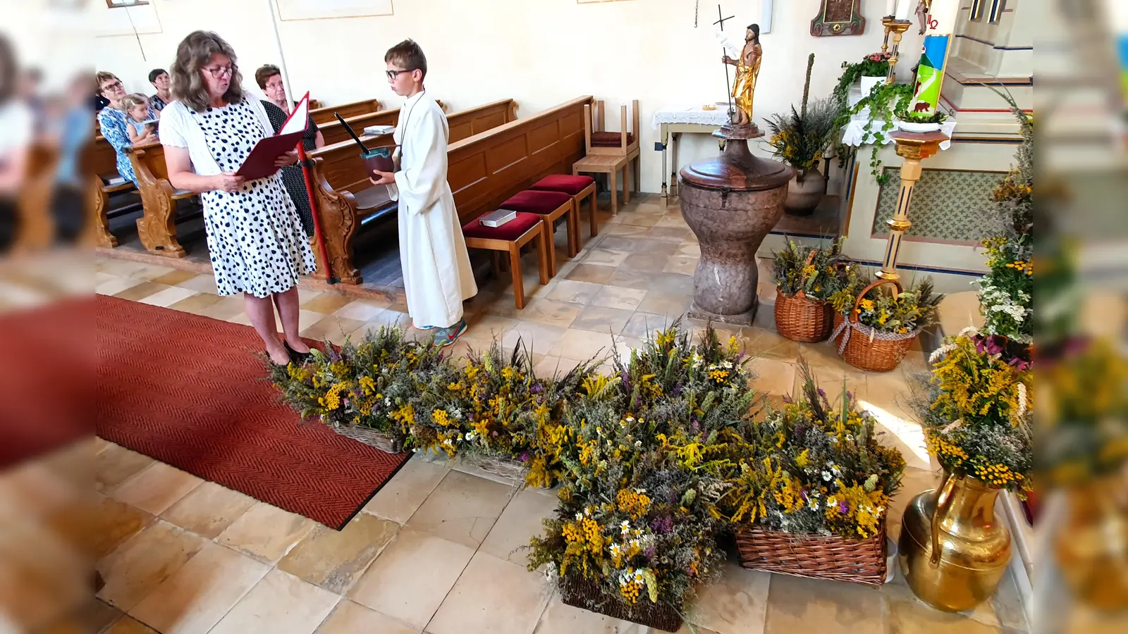 Nach dem Segensgebet durch Wortgottesdienstleiterin Zita Reischl wurden die geweihten Buschen an die Gottesdienstbesucher verteilt. (Foto: Pfarrgemeinderat)